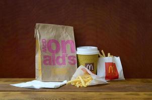 KHARKOV, UKRAINE - MAY 12, 2022 McDonald's take away paper bag and junk food on wooden table photo
