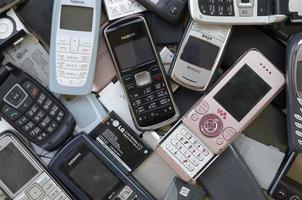 KHARKOV, UKRAINE - MAY 12, 2022 Bunch of old used outdated mobile phones and batteries. Recycling electronics photo