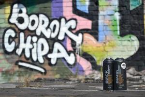 KHARKOV. UKRAINE - MAY 17, 2022 Used Montana black aerosol spray cans against graffiti paintings. MTN or Montana-cans is manufacturer of high pressure spray paint goods photo