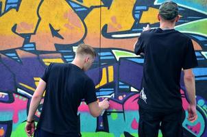 KHARKOV. UKRAINE - MAY 2, 2022 Festival of street arts. Young guys draw graffiti on portable wooden walls in the center of the city. The process of painting on walls with aerosol spray cans photo