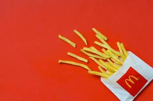 KHARKOV, UKRAINE - MAY 12, 2022 McDonald's French fries in small paperbag on bright red background photo