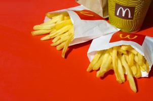 KHARKOV. UKRAINE - MAY 17, 2022 McDonald's French fries in small paperbag and coffee cup on bright red background photo