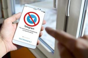 KHARKOV, UKRAINE - APRIL 27, 2022 A mobile phone with the Telegram app screen with a prohibiting sign. Roskomnadzor blocked the Telegram service in Russia. Access to telegram messenger is closed photo