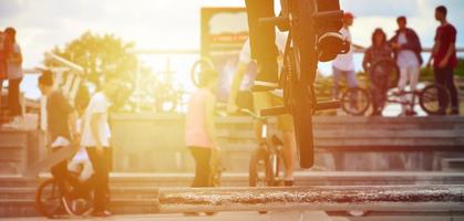 un ciclista salta sobre una tubería en una bicicleta bmx. mucha gente con bicicletas en el fondo. concepto de deportes extremos foto