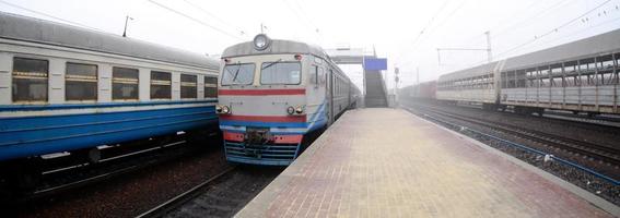 la vía férrea en una mañana brumosa. el tren suburbano ucraniano está en la estación de pasajeros. foto de ojo de pez con mayor distorsión