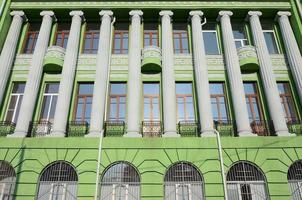 Restored old multi-storey building with antique columns, painted in green photo