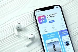 KHARKOV, UKRAINE - MAY 12, 2022 Apple music for artists icon and application from App store on iPhone 12 pro display screen with airpods pro on white table photo