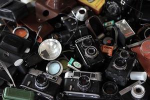 KHARKOV, UKRAINE - MAY 12, 2022 Film photo cameras and another old retro photo equipment on black wooden table in photographer darkroom. Photographic gear from soviet union