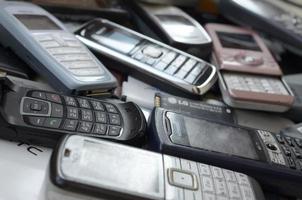 KHARKOV, UKRAINE - MAY 12, 2022 Bunch of old used outdated mobile phones and batteries. Recycling electronics photo