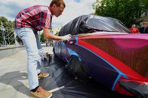 kharkov, ucrania - 27 de mayo de 2022 festival de arte callejero. los jóvenes dibujan graffiti en la carrocería del auto en el centro de la ciudad. el proceso de dibujo de graffiti de color en un coche con latas de aerosol foto