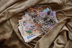 Bunch of stolen jewelry and money on military uniform cloth fabric. Looting by Russian soldiers in the Ukrainian cities during the Russian attack on Ukraine. Marauders and looters photo