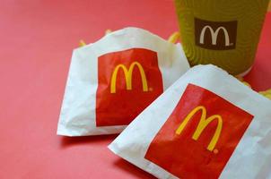 KHARKOV. UKRAINE - MAY 17, 2022 McDonald's French fries in small paperbag and coffee cup on bright red background photo