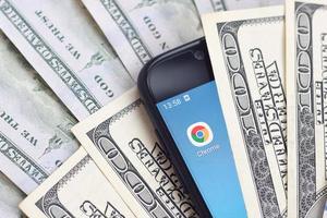 KHARKOV. UKRAINE - MAY 17, 2022 Smartphone screen with Google chrome app and lot of hundred dollar bills. Business and social networking concept photo