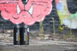KHARKOV. UKRAINE - MAY 2, 2022 Used Montana black aerosol spray cans against graffiti paintings. MTN or Montana-cans is manufacturer of high pressure spray paint goods photo
