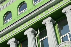 Restored old multi-storey building with antique columns, painted in green photo