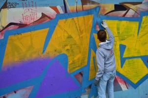 KHARKOV. UKRAINE - MAY 2, 2022 Festival of street arts. Young guys draw graffiti on an old concrete walls in the center of the city. The process of painting on walls with aerosol spray cans photo