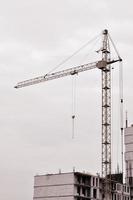 Working tall cranes inside place for with tall buildings under construction against a clear blue sky. Crane and building working progress. Retro tone photo