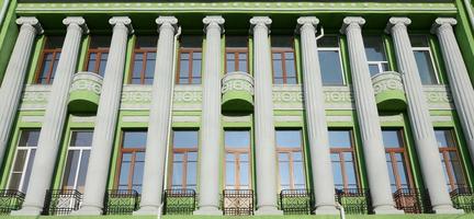 Restored old multi-storey building with antique columns, painted in green photo