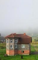 el edificio de apartamentos se encuentra frente a una espesa capa de niebla. vivir en una zona montañosa en los cárpatos, ucrania foto