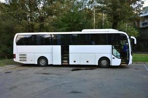 autobús turístico blanco para excursiones. el autobús está estacionado en un estacionamiento cerca del parque foto