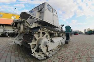 Photo of a gray bulldozer among the railway trains. Strong distortion from the fisheye lens