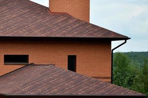 The house is equipped with high-quality roofing of shingles bitumen tiles. A good example of perfect roofing. The roof is reliably protected from adverse weather conditions photo