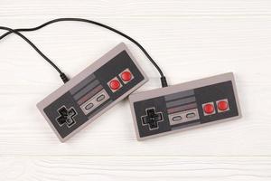 Jarkov. ucrania - 17 de mayo de 2022 dos gamepads antiguos para consolas de videojuegos de 8 bits sistema de entretenimiento nintendo y nes mini en mesa blanca. juegos retro de la vieja escuela foto