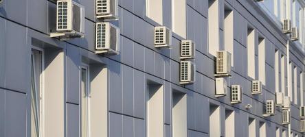 Gray wall of office building made of metal plates with windows and air conditioners photo