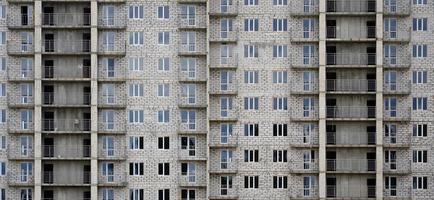 Textured pattern of a russian whitestone residential house building wall with many windows and balcony under construction photo