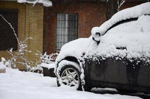 fragmento del coche bajo una capa de nieve después de una fuerte nevada. el cuerpo del coche está cubierto de nieve blanca foto