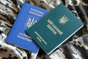 Ukrainian military ID and foreign passport on fabric with texture of pixeled camouflage. Cloth with camo pattern in grey, brown and green shapes with Ukrainian army personal token and passport. photo