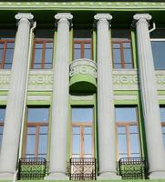 Restored old multi-storey building with antique columns, painted in green photo