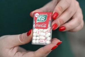 KHARKOV. UKRAINE - MAY 17, 2022 Young girl holds Tic-tac hard mints pack with coca-cola taste. Tic Tac is a brand of small hard mints, produced by Ferrero photo