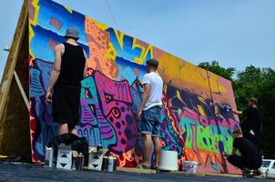 KHARKOV, UKRAINE - MAY 27, 2022 Festival of street arts. Young guys draw graffiti on portable wooden walls in the center of the city. The process of painting on walls with aerosol spray cans photo