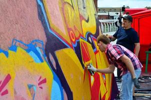 KHARKOV, UKRAINE - MAY 27, 2022 Festival of street arts. Young guys draw graffiti on portable wooden walls in the center of the city. The process of painting on walls with aerosol spray cans photo