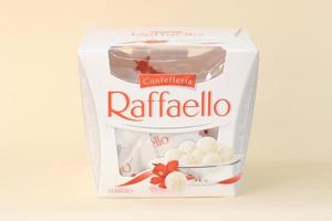 KHARKOV. UKRAINE - MAY 2, 2022 Raffaello candies on beige background. Raffaello is a spherical coconut almond confection that Italian manufacturer Ferrero brought to the market in 1990 photo