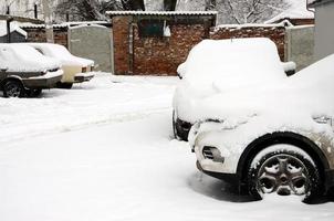 fragmento del coche bajo una capa de nieve después de una fuerte nevada. el cuerpo del coche está cubierto de nieve blanca foto