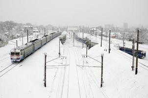 un largo tren de turismos se mueve a lo largo de la vía férrea. paisaje ferroviario en invierno después de la nevada foto