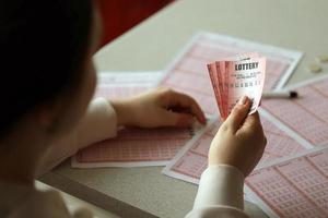 Filling out a lottery ticket. A young woman holds the lottery ticket with complete row of numbers on the lottery blank sheets background. photo