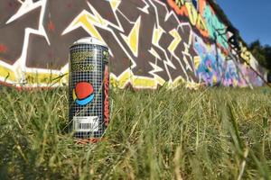 KHARKOV. UKRAINE - MAY 17, 2022 Used Montana hardcore aerosol spray can against graffiti paintings. MTN or Montana-cans is manufacturer of high pressure spray paint goods photo