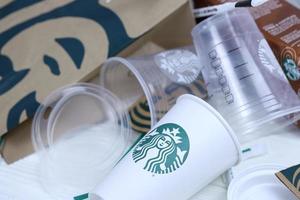 KHARKOV, UKRAINE - MAY 12, 2022 Starbucks disposable used production on white table. Starbucks Corporation is multinational chain of coffeehouses headquartered in Seattle, Washington photo