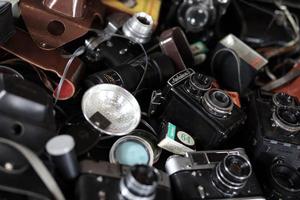 KHARKOV. UKRAINE - MAY 2, 2022 Film photo cameras and another old retro photo equipment on black wooden table in photographer darkroom. Photographic gear from soviet union