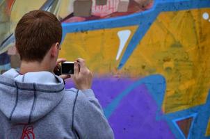 KHARKOV. UKRAINE - MAY 2, 2022 Festival of street arts. Young guys draw graffiti on an old concrete walls in the center of the city. The process of painting on walls with aerosol spray cans photo