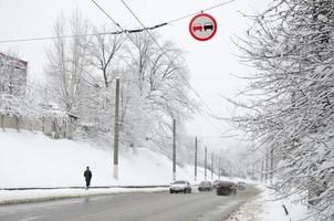 está prohibido adelantar. la señal prohíbe adelantar a todos los vehículos en el tramo de carretera. una señal de tráfico que cuelga sobre un camino cubierto de nieve foto