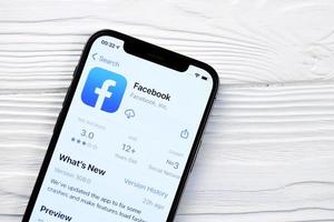 kharkov, ucrania - 12 de mayo de 2022 icono de facebook y aplicación de la tienda de aplicaciones en la pantalla de visualización del iphone 12 pro en la mesa blanca foto