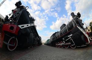 Photo of old black steam locomotives of the Soviet Union. Strong distortion from the fisheye lens