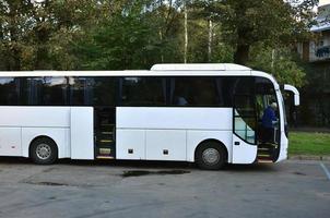 autobús turístico blanco para excursiones. el autobús está estacionado en un estacionamiento cerca del parque foto