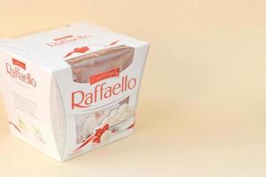 KHARKOV. UKRAINE - MAY 2, 2022 Raffaello candies on beige background. Raffaello is a spherical coconut almond confection that Italian manufacturer Ferrero brought to the market in 1990 photo