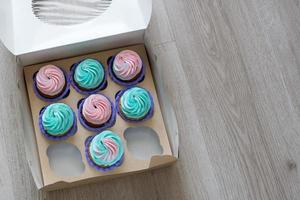 a box of cupcakes with two empty space lies diagonally on the table flatlay photo