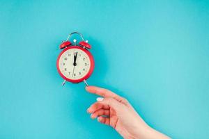 Woman hand holding the red vintage alarm clock photo